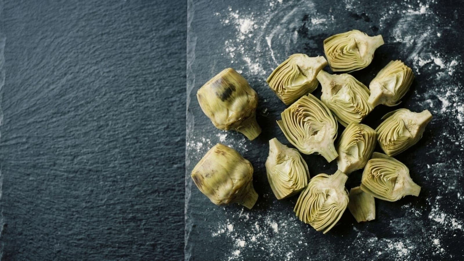 Oil-packed artichoke hearts, whole and quartered, on dark slate