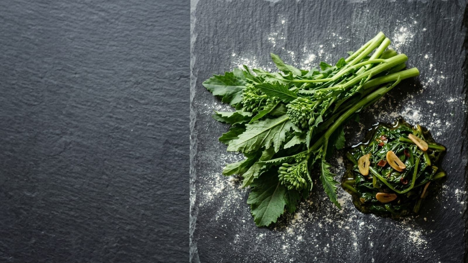 A fresh bunch of broccoli rabe beside a small pile of sautéed friarielli glistening with olive oil, on dark slate